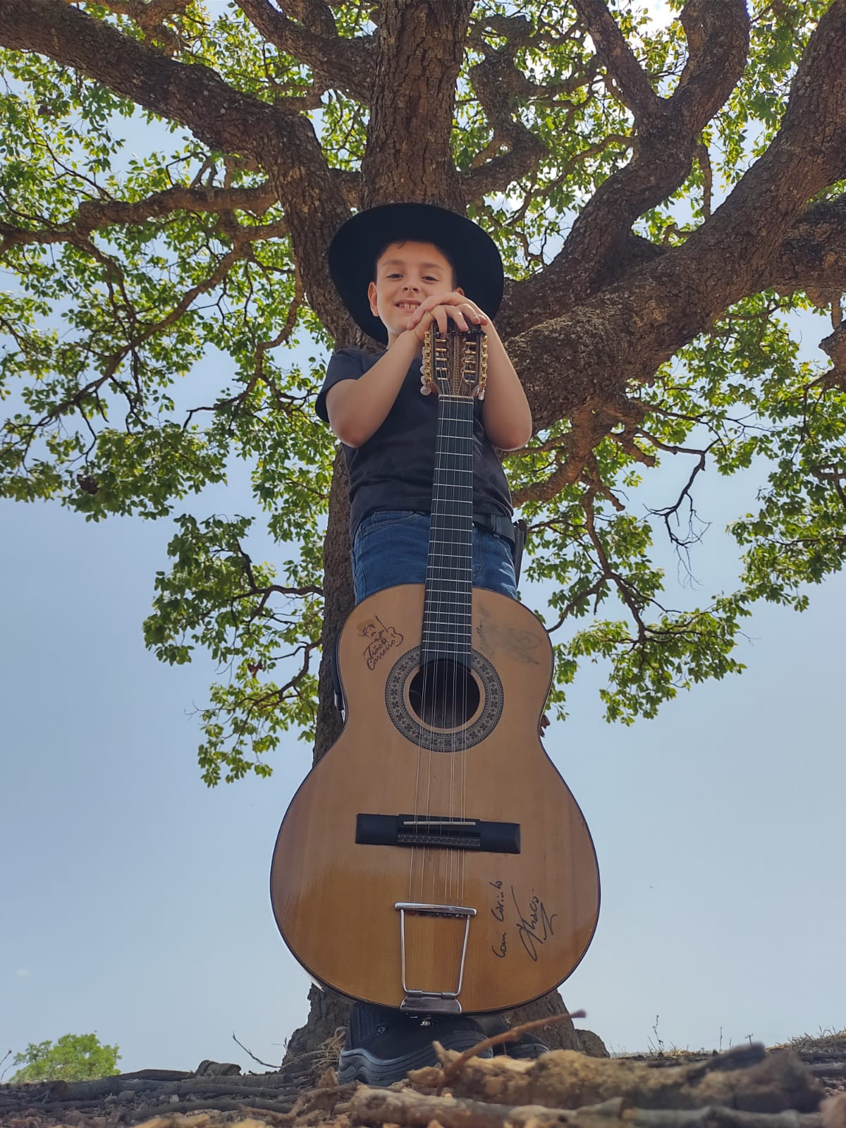 Pietro Violla com sua viola caipira junto à árvore